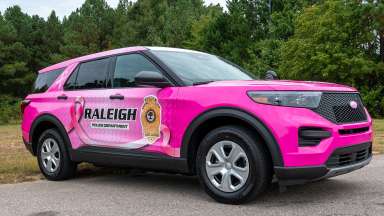 A pink police cruiser with Raleigh Police Department on side with logo and pink awareness ribbon
