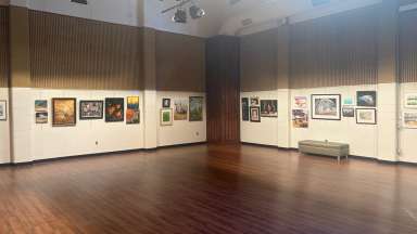 paintings hanging in a large room with white walls and a wooden floor