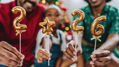 Festive family celebrating the new year at home, holding golden balloons with the numbers 2026