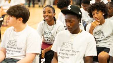 Four boys with "Raleigh Youth Summer Employment Program" white t-shirts sitting in chairs