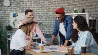 A group of adults huddle around a table planning something for their organization
