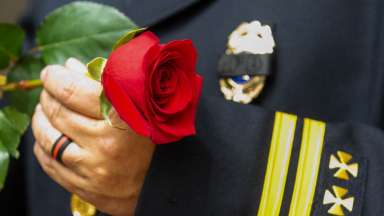 Firefighter in dress uniform holding red rose flower