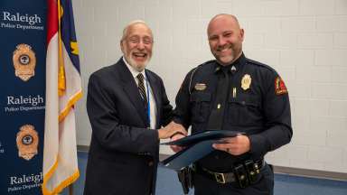 Raleigh police officer handing folder to community member
