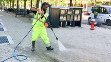 A City of Raleigh employee powerwashing a sidewalk