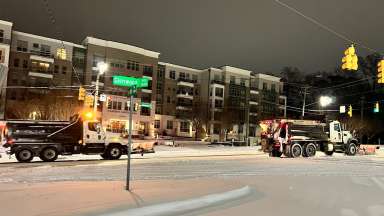 Two snow plows on snowy road, with snow coming down