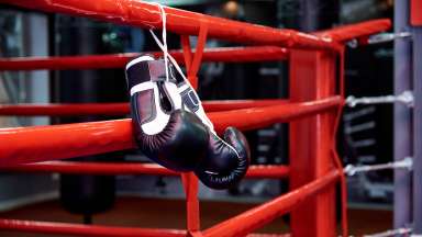 boxing gloves hanging by a string on a boxing ring rope