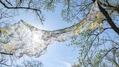 A weaving is suspended above a greenway