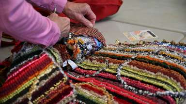 Instructor's hands working on a multi-colored beaded artwork