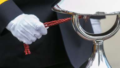 White gloved hand ringing silver bell