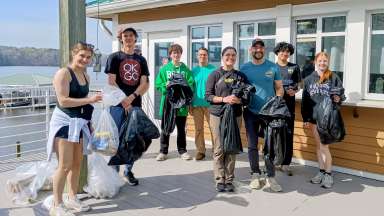 a group of volunteers at lake Wheeler, smiling and holding trash bags