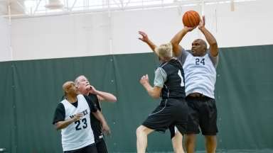 four men playing basketball in the senior games with one shooting a jump shot