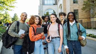 teens smiling outside carrying backpacks