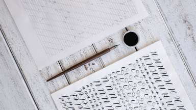 calligraphy sheets, nibs, paper, ink on a wooden background