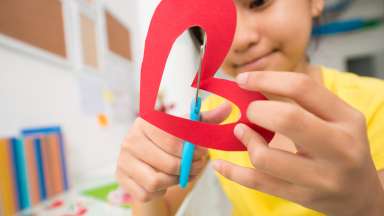 a kid crafting a heart out of paper