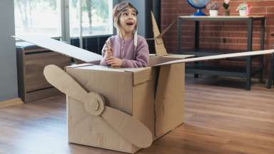 a kid dressed up as a aviator with a card board airplane