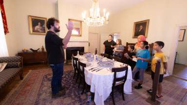 a person speaking to a group of people inside a historic room
