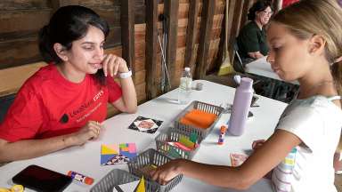 a child at a table doing crafts with a volunteer