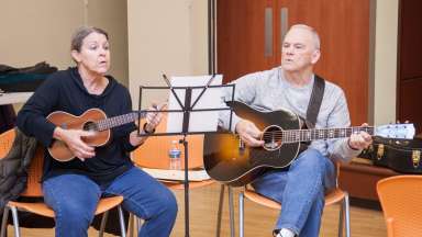 a person play a Ukulele and another playing a guitar