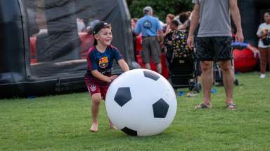 a child playing with an extra large soccer ball in a field at an event