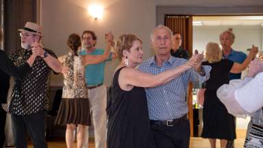 couples doing ballroom dancing in a room with other couples