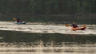 people on kayaks in a lake at sunrise