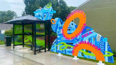 Brightly colored metal art is attached to a bus shelter
