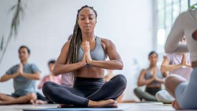 A small group of adults on yoga mats with their legs crossed in a Yoga class