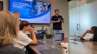 a person speaking to a group of teens in a conference room