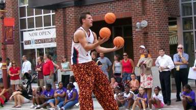 a person outdoors juggling 3 mini-basketballs