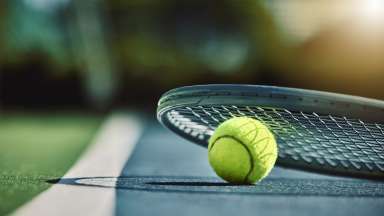 a close image of a tennis racquet and ball on a tennis court