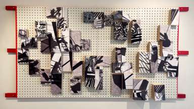 mixed media work with wood and a peg board by Jason Lord in black and white with accents of red