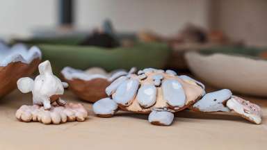 clay sculptures of a turtle and elephant, glazed and awaiting firing