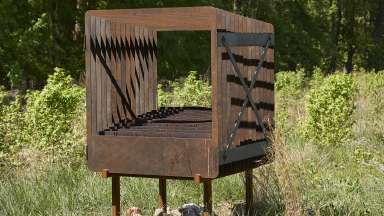 A sculpture made of corten steel lasercut panels in the middle of a field.