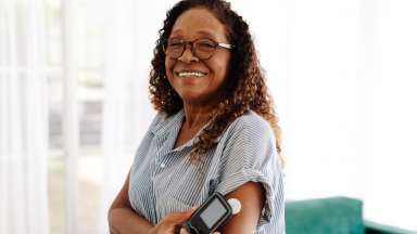 a person smiling wearing a continuous glucose monitoring device