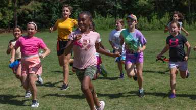 a group of girls outside running in a field