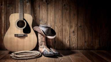 boots, guitar, and cowboy sitting on a wood floor