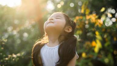 young child relaxing and breathing fresh air at park