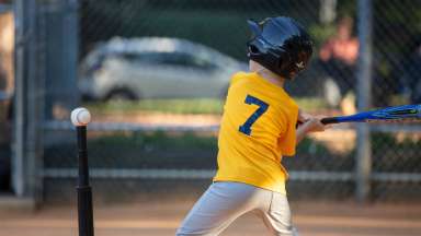 a child swinging bat at tee while playing tee-ball