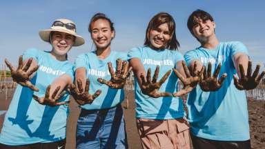 4 teens with matching blue shirts, showing their dirty hands