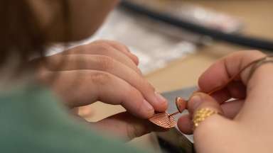 Student working on a piece of copper jewelry