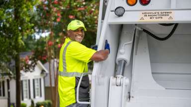 Solid Waste crew member on the back of a collection truck