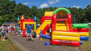 a festival with people, tents and inflatable slides