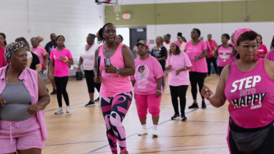 Group of individuals dancing in a gym in pink