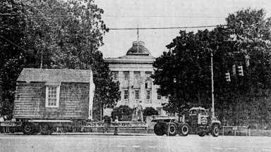 a vintage photo of a truck pulling a small house on a trailer