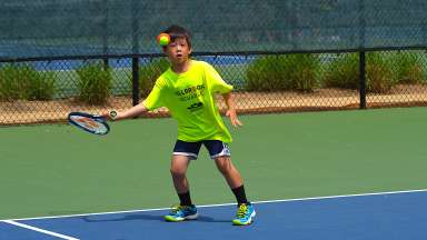 a child playing tennis on an outdoor court