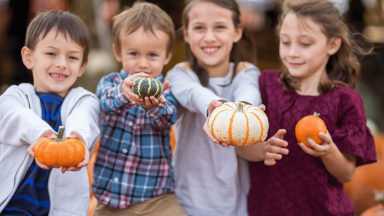Four kids holding small pumpkins