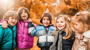 Four children smiling with a fall background