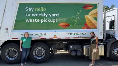 Two employees pointing to yard waste truck