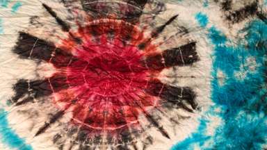 A batik pattern on fabric in reds and blues.