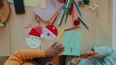a child and adult hands doing holiday crafts